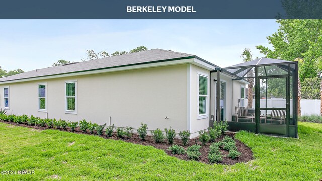 view of home's exterior with glass enclosure and a yard