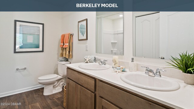 bathroom featuring a shower, hardwood / wood-style flooring, vanity, and toilet