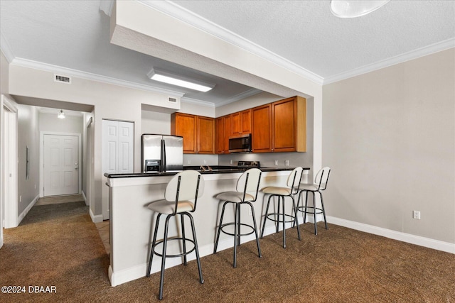 kitchen with stainless steel appliances, a textured ceiling, ornamental molding, carpet, and a kitchen breakfast bar