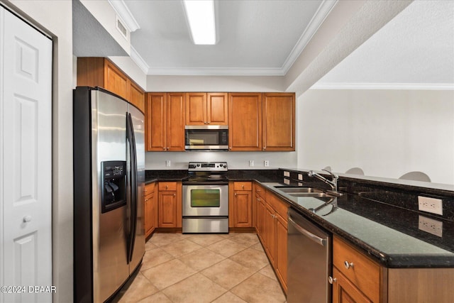 kitchen with crown molding, dark stone counters, stainless steel appliances, sink, and kitchen peninsula