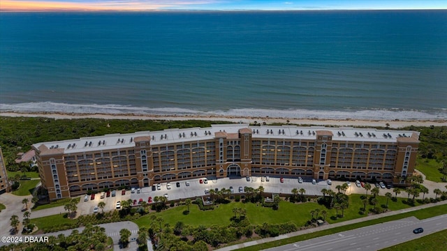 aerial view at dusk featuring a beach view and a water view