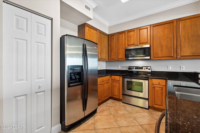 kitchen featuring stainless steel appliances, sink, ornamental molding, dark stone countertops, and light tile patterned floors