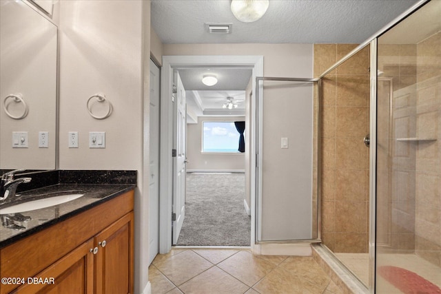 bathroom featuring vanity, a shower with shower door, tile patterned flooring, and a textured ceiling