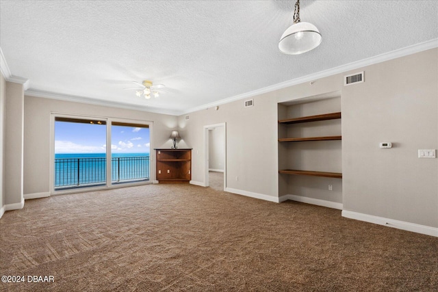 unfurnished living room with a textured ceiling, a water view, crown molding, and carpet