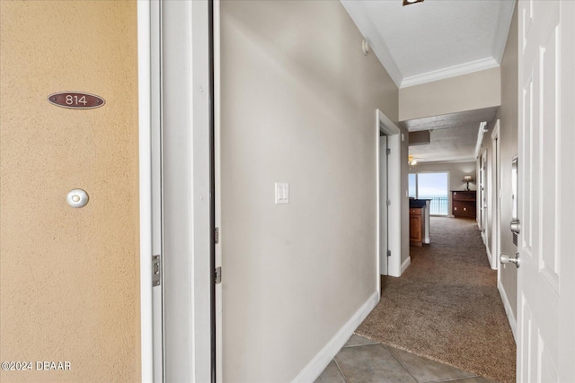 hall with a textured ceiling, carpet, and ornamental molding