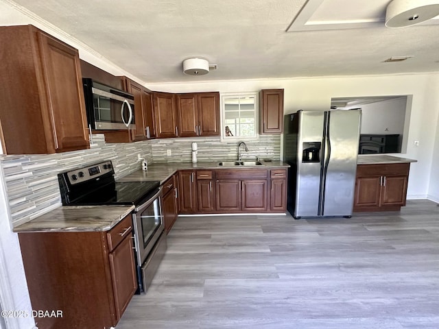 kitchen featuring visible vents, decorative backsplash, a sink, light wood-style flooring, and appliances with stainless steel finishes