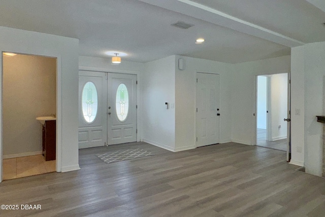 foyer featuring baseboards, visible vents, and wood finished floors