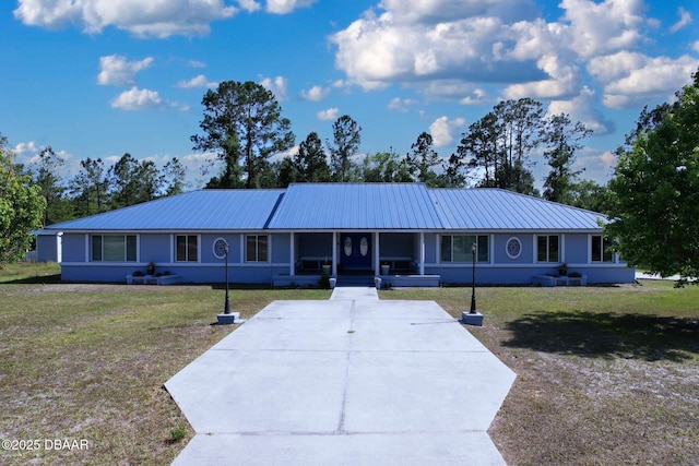 view of front of home featuring driveway, metal roof, and a front yard