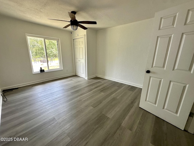 unfurnished bedroom with a closet, a textured ceiling, dark wood-style flooring, and baseboards