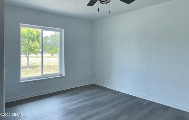 spare room with baseboards, a ceiling fan, and dark wood-type flooring