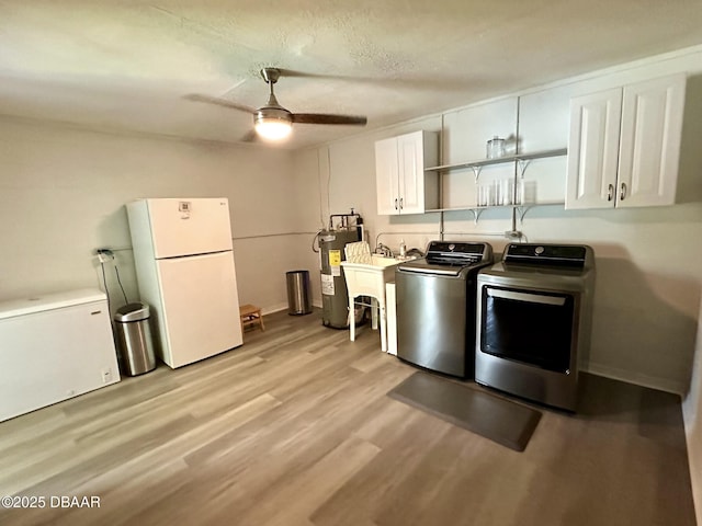 kitchen with ceiling fan, independent washer and dryer, white cabinets, freestanding refrigerator, and electric water heater