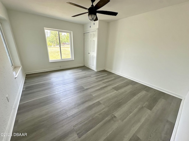 unfurnished bedroom with a ceiling fan, baseboards, wood finished floors, and a closet