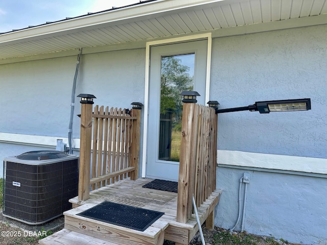 doorway to property with central AC unit and stucco siding