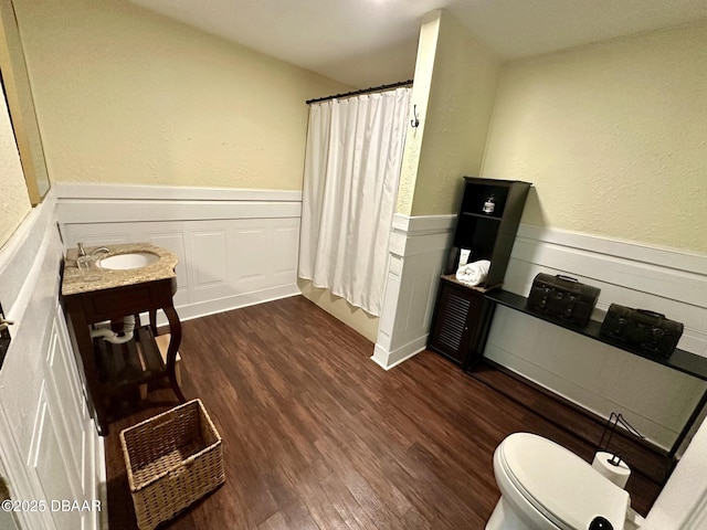 bathroom featuring wainscoting, a shower with shower curtain, wood finished floors, and toilet