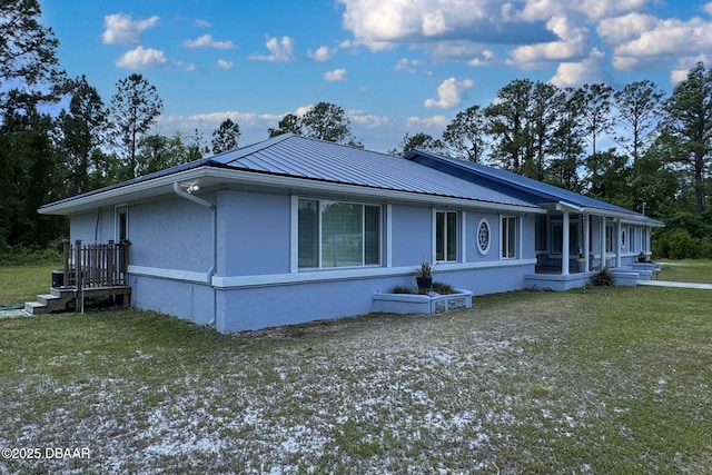 exterior space featuring a lawn, a standing seam roof, metal roof, and stucco siding