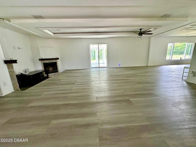 unfurnished living room featuring ceiling fan, a fireplace, wood finished floors, and visible vents
