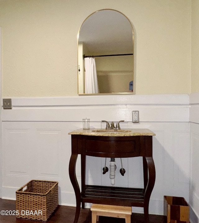 full bath with a wainscoted wall, vanity, and a decorative wall