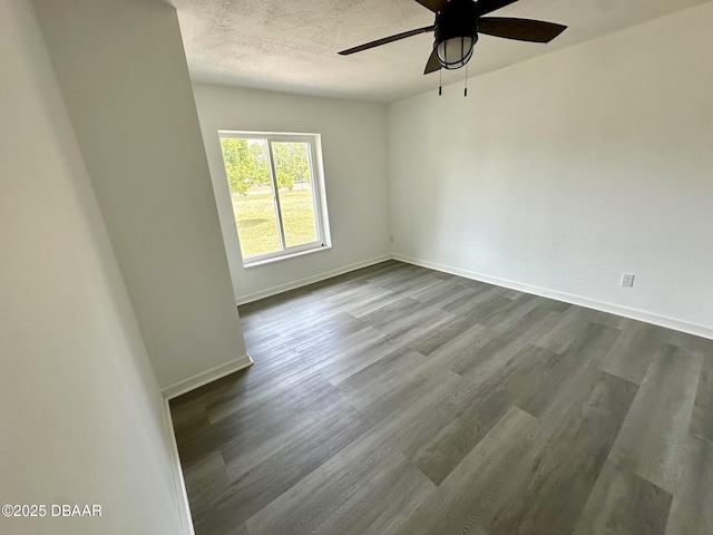unfurnished room featuring a ceiling fan, baseboards, a textured ceiling, and dark wood-type flooring