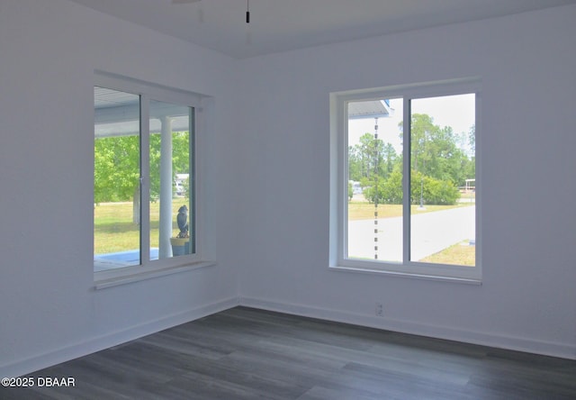 empty room featuring a ceiling fan, dark wood finished floors, and a healthy amount of sunlight
