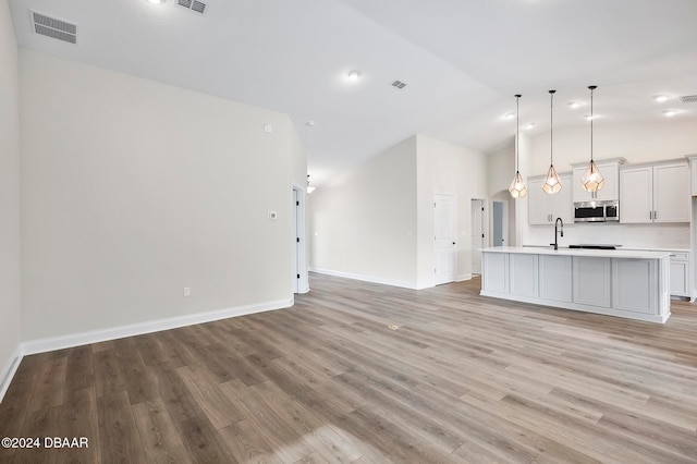 unfurnished living room featuring light hardwood / wood-style floors, sink, and vaulted ceiling