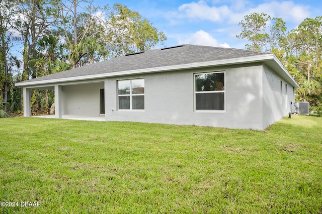 rear view of property featuring a lawn, central AC, and a patio area