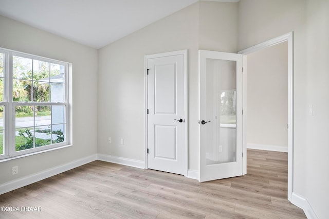 unfurnished bedroom with light wood-type flooring and vaulted ceiling