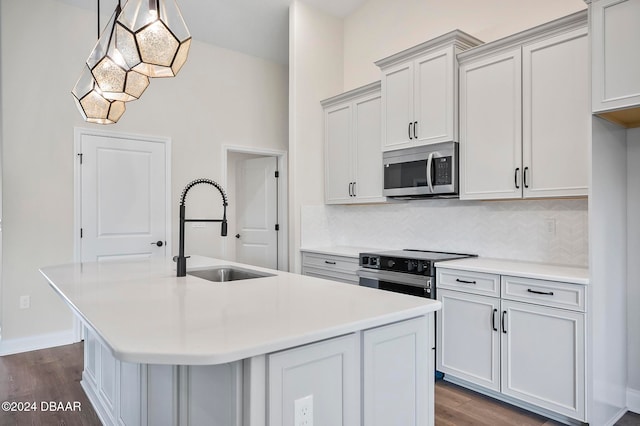 kitchen featuring sink, appliances with stainless steel finishes, dark hardwood / wood-style floors, an island with sink, and pendant lighting