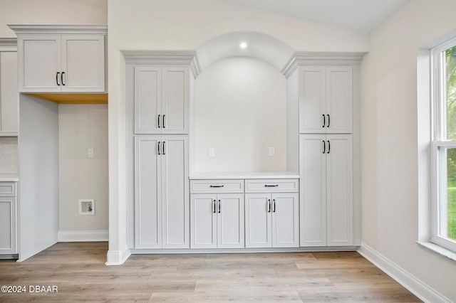 kitchen featuring white cabinets, light wood-type flooring, plenty of natural light, and lofted ceiling