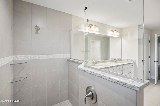 bathroom with vanity, tile walls, tile patterned flooring, and tiled shower