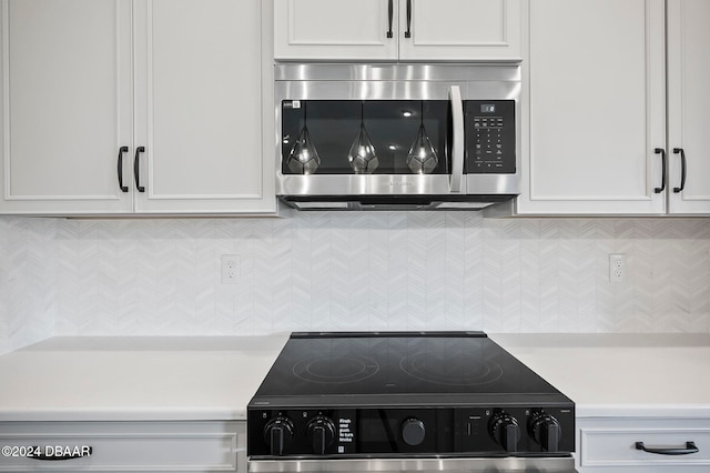 details with backsplash, white cabinets, and stainless steel appliances