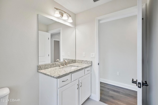 bathroom featuring toilet, vanity, and wood-type flooring