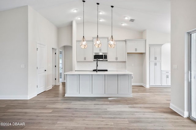 kitchen with pendant lighting, light hardwood / wood-style flooring, white cabinets, and an island with sink