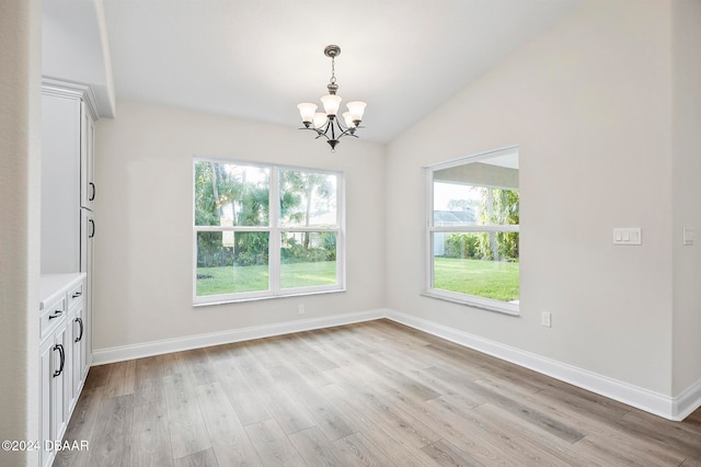 unfurnished dining area with a chandelier, light hardwood / wood-style flooring, and lofted ceiling