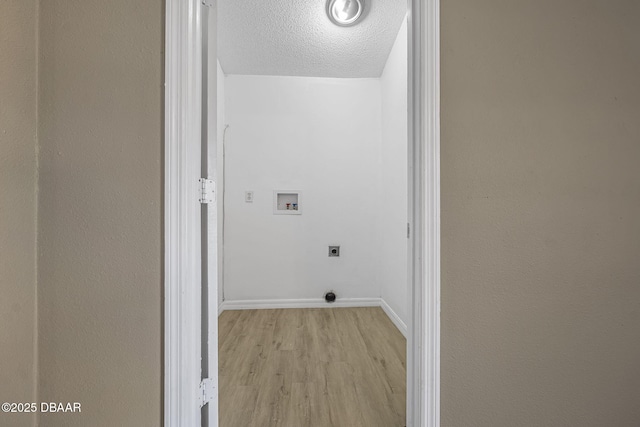 laundry area featuring hookup for an electric dryer, light hardwood / wood-style floors, hookup for a washing machine, and a textured ceiling