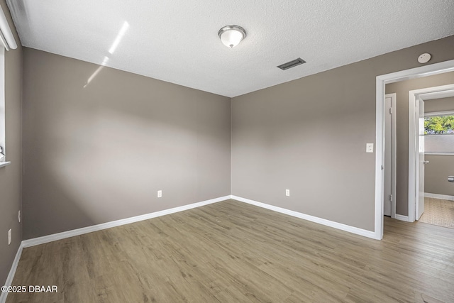 spare room with a textured ceiling and light hardwood / wood-style flooring