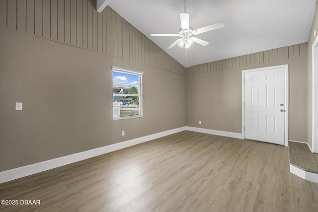 spare room featuring light hardwood / wood-style flooring, lofted ceiling with beams, and ceiling fan