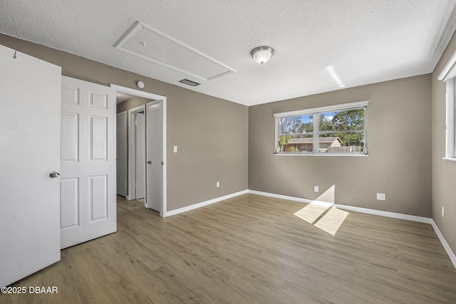 unfurnished room featuring light hardwood / wood-style flooring and a textured ceiling