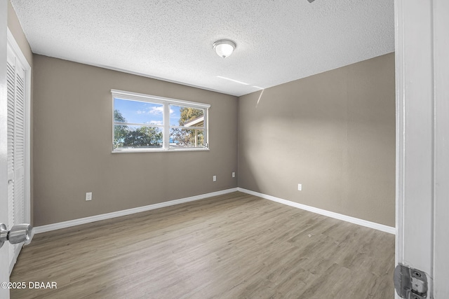 unfurnished room featuring light hardwood / wood-style floors and a textured ceiling