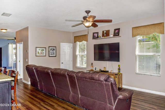 living room featuring visible vents, baseboards, dark wood finished floors, a ceiling fan, and a textured ceiling