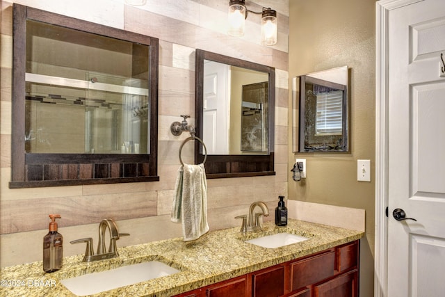 full bath featuring double vanity, a stall shower, backsplash, and a sink