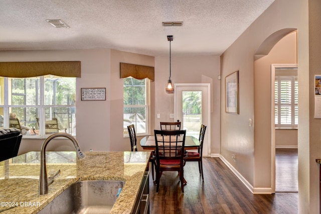 dining area with dark wood-type flooring, visible vents, a textured ceiling, and baseboards