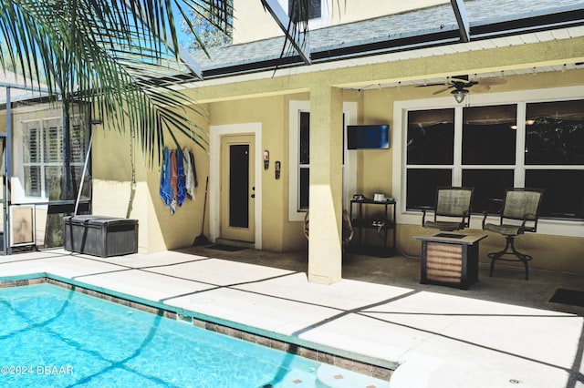 outdoor pool featuring glass enclosure, a patio area, and ceiling fan