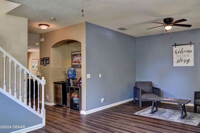 sitting room featuring beverage cooler, wood finished floors, visible vents, baseboards, and stairway