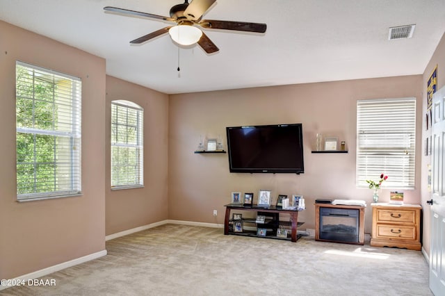 carpeted living area featuring a ceiling fan, visible vents, and baseboards