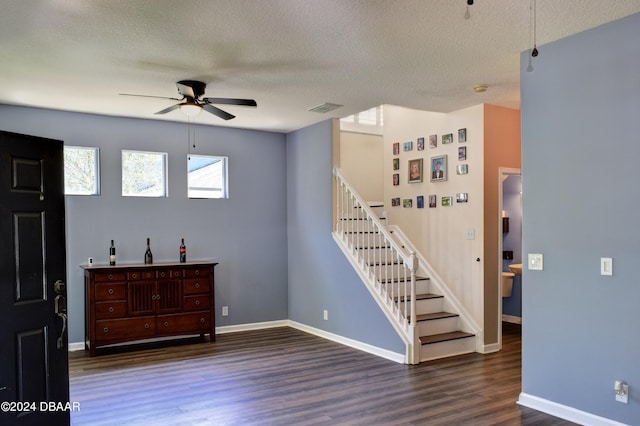 empty room featuring ceiling fan, stairs, visible vents, and dark wood finished floors