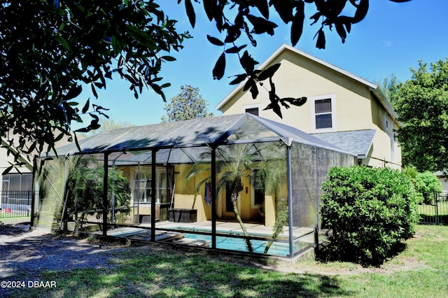 back of property featuring a fenced in pool, a patio, stucco siding, glass enclosure, and fence