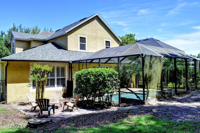 rear view of property featuring roof with shingles, a patio, stucco siding, glass enclosure, and an outdoor pool