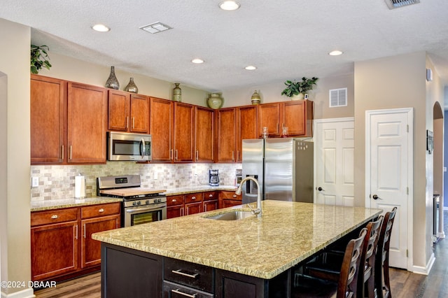 kitchen featuring appliances with stainless steel finishes, a sink, visible vents, and tasteful backsplash