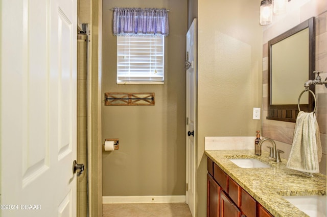 bathroom featuring double vanity, a sink, baseboards, and tile patterned floors