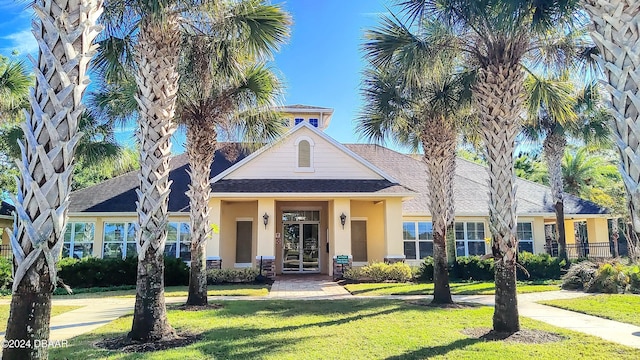 view of front of home with a shingled roof, a front lawn, and stucco siding